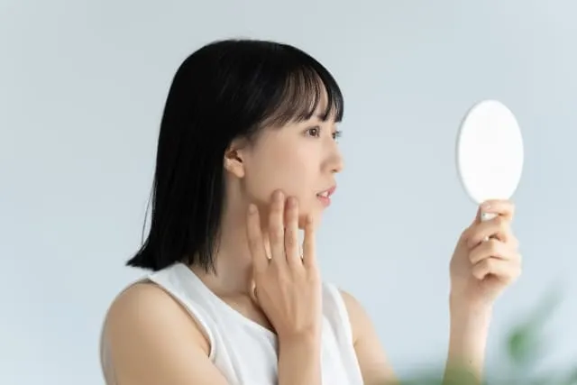 フェイシャルサロンでの効果を鏡を見て確認している女性