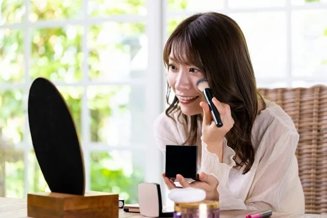 自分の顔にメイクをしている女性